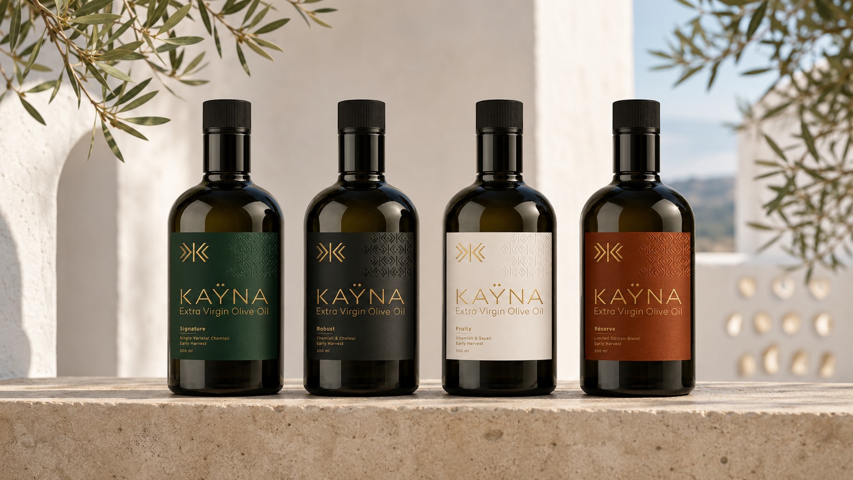 Les quatre créations KAŸNA — Signature, Robust, Fruity et Réserve — sur un muret de pierre blanche, dans la lumière méditerranéenne